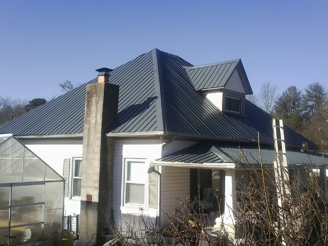 Dark blue standing seam metal roof on a white farmhouse with dormer — Slate & Tile Roof Repair by Roofing Brothers in Wenonah