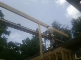 Carpenter setting a ridge beam over a new addition frame — Ice Dam Removal by Roofing Brothers in Wenonah