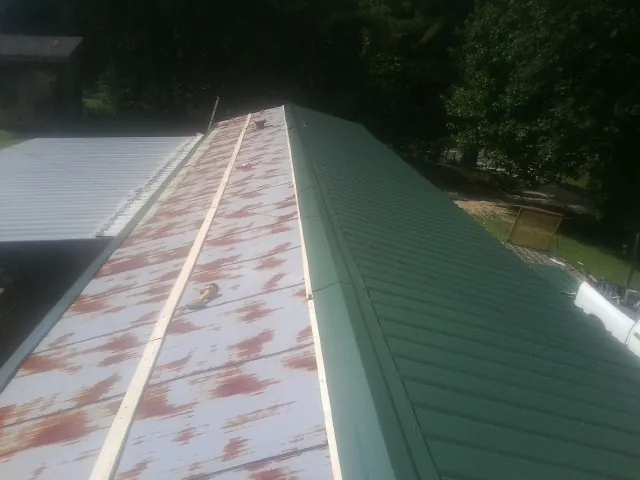 Old rusted panels beside newly installed green metal roofing — Wind Damage Roof Repair by Roofing Brothers in Wenonah
