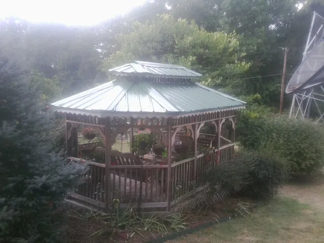 Green metal roof on a backyard gazebo surrounded by garden beds in Wenonah