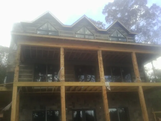 Dormers and porch framing on a large log home under construction — Roof Coating work by our crew in Wenonah