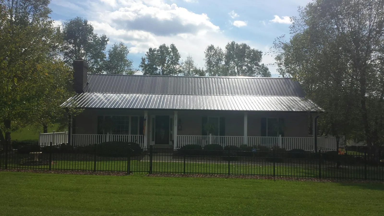 Gray metal roof on a brick ranch with a full width front porch — Gutter Guard Installation work by our crew in Wenonah