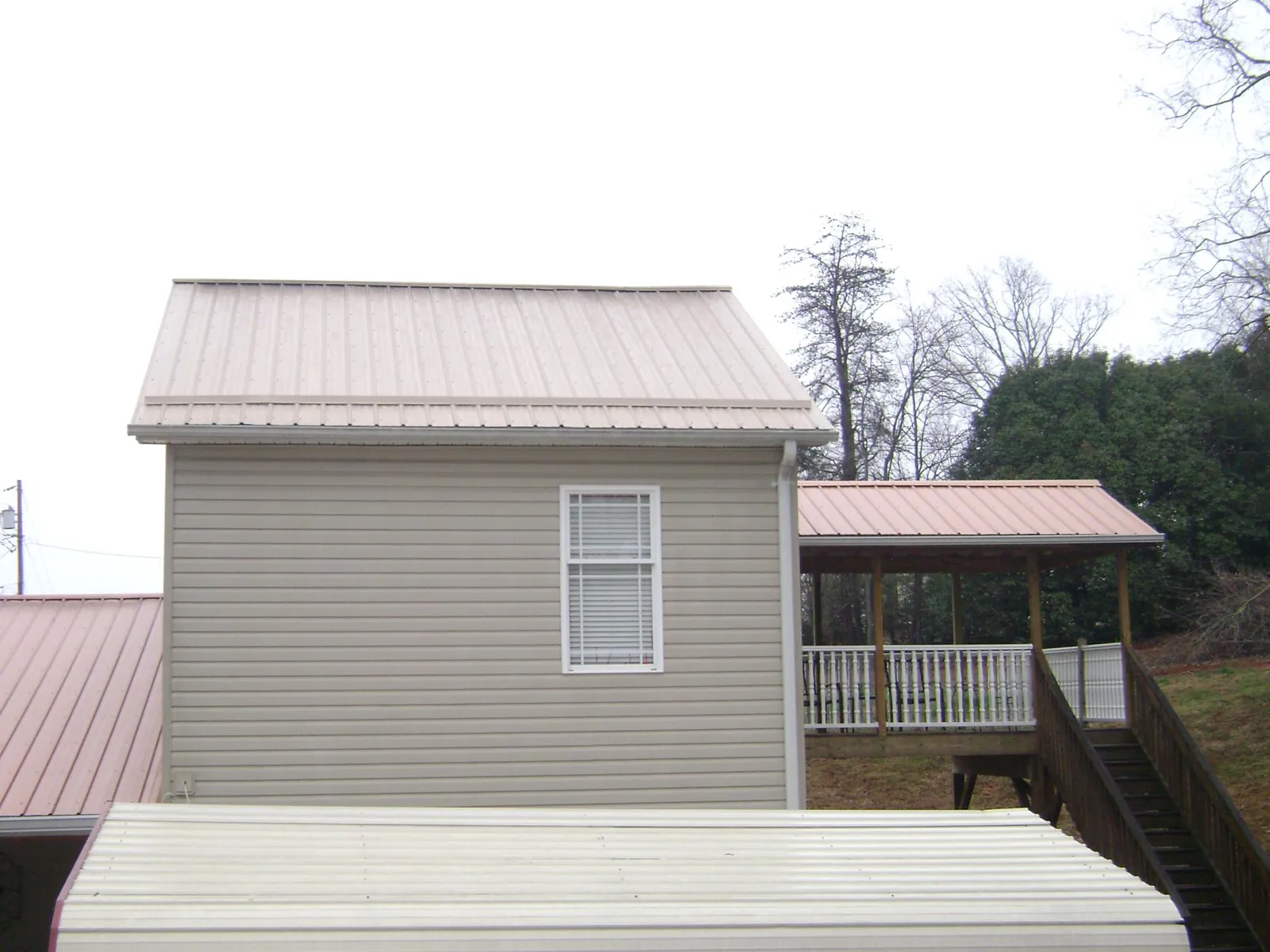 Tan metal roofs on a two story addition and attached porch, from a Roof Replacement job in Wenonah