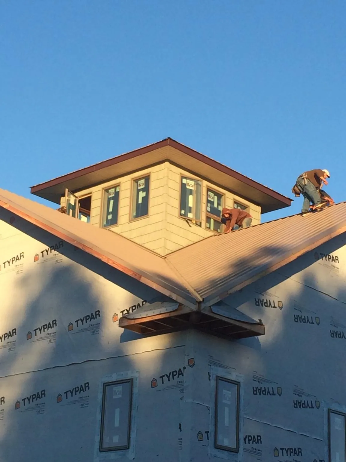 Roofers working around a rooftop cupola on a new metal roof at sunset — Roof Waterproofing in Wenonah by Roofing Brothers